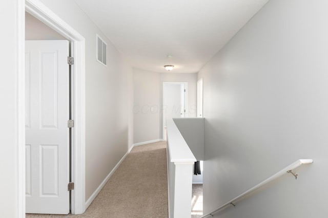 hall featuring an upstairs landing, visible vents, light carpet, and baseboards