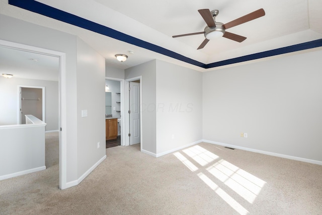 empty room with light carpet, a ceiling fan, and baseboards