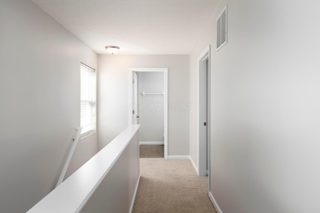 corridor featuring visible vents, baseboards, carpet, and an upstairs landing