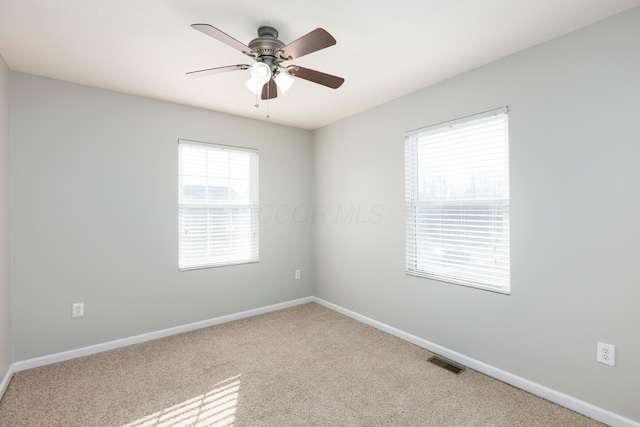 carpeted empty room featuring baseboards, visible vents, and ceiling fan