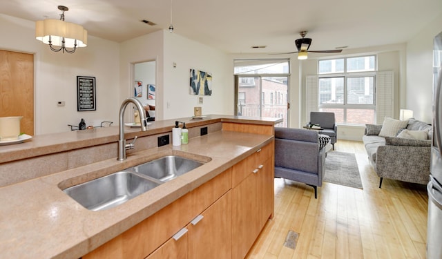 kitchen with decorative light fixtures, visible vents, light wood-style floors, open floor plan, and a sink