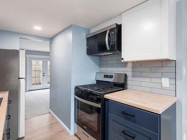 kitchen featuring stainless steel appliances, tasteful backsplash, white cabinets, blue cabinets, and baseboards