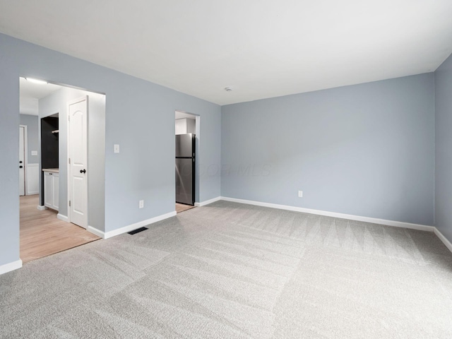 unfurnished room featuring visible vents, light colored carpet, and baseboards