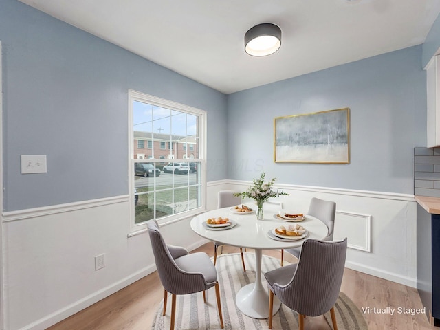 dining area with a wainscoted wall, light wood-type flooring, and baseboards