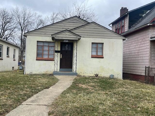 bungalow-style house with stucco siding and a front yard