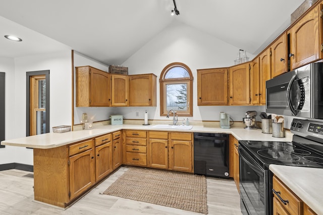 kitchen with a peninsula, black appliances, light countertops, and a sink