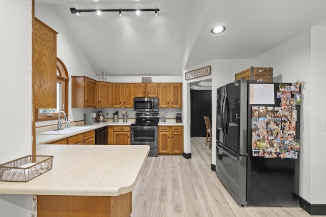 kitchen featuring light countertops, lofted ceiling, appliances with stainless steel finishes, brown cabinetry, and a sink