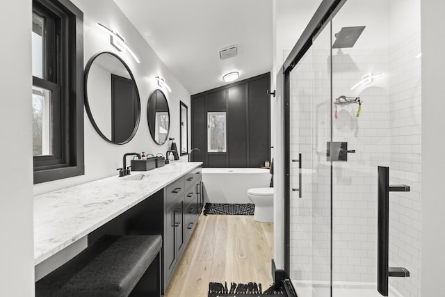 bathroom featuring vanity, wood finished floors, visible vents, a stall shower, and a freestanding bath