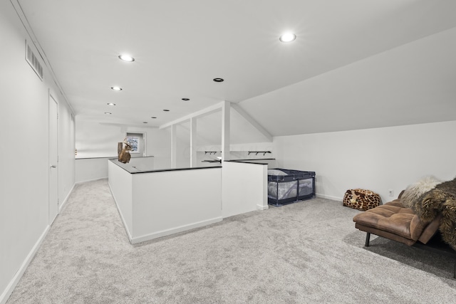 kitchen with visible vents, dark countertops, open floor plan, light colored carpet, and vaulted ceiling