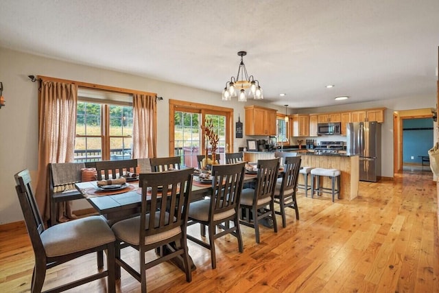 dining area with light wood finished floors, recessed lighting, and a notable chandelier