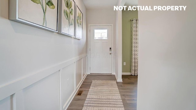 doorway to outside with a wainscoted wall, wood finished floors, and a decorative wall