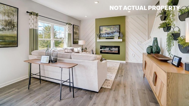 living room with a glass covered fireplace, recessed lighting, baseboards, and wood finished floors