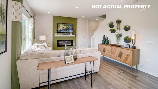 living room with recessed lighting, baseboards, wood finished floors, and a glass covered fireplace