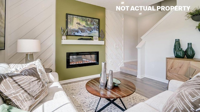 living area featuring baseboards, stairs, recessed lighting, wood finished floors, and a glass covered fireplace