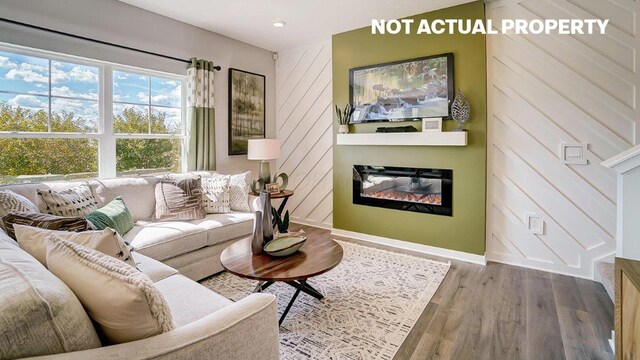 living room with a glass covered fireplace, recessed lighting, wood finished floors, and baseboards