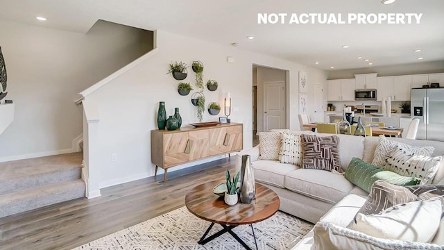 living room featuring stairs, recessed lighting, baseboards, and light wood finished floors