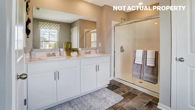 full bathroom with double vanity, a shower stall, stone finish flooring, and a sink