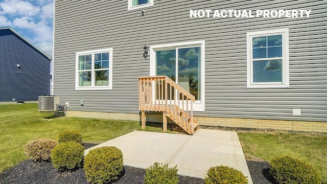 view of exterior entry with central air condition unit, a patio, and a yard