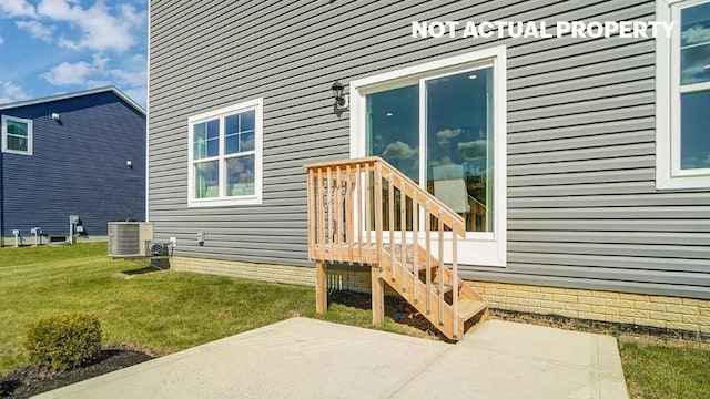 entrance to property featuring central air condition unit, a patio, and a lawn