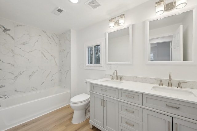 full bathroom featuring toilet, wood finished floors, a sink, and visible vents