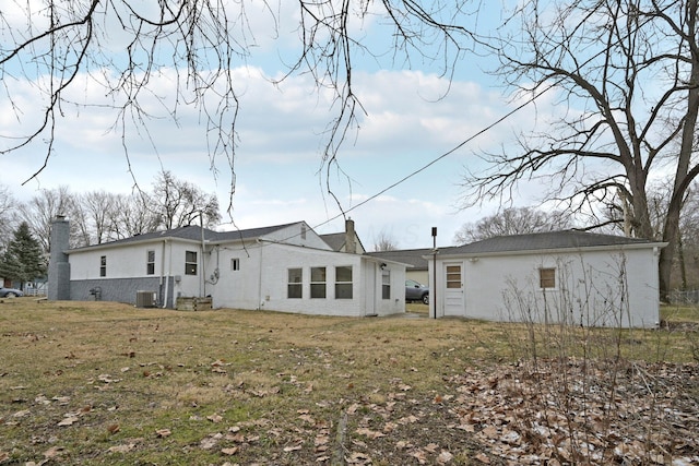 rear view of property with a chimney and a yard