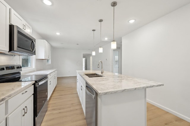 kitchen featuring appliances with stainless steel finishes, light wood-style floors, a sink, and tasteful backsplash