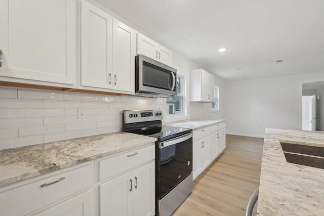 kitchen featuring stainless steel appliances, light wood finished floors, light stone countertops, and white cabinets