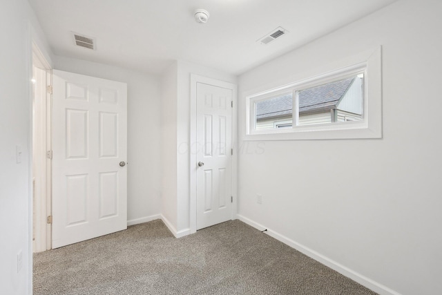 unfurnished bedroom with carpet floors, baseboards, and visible vents