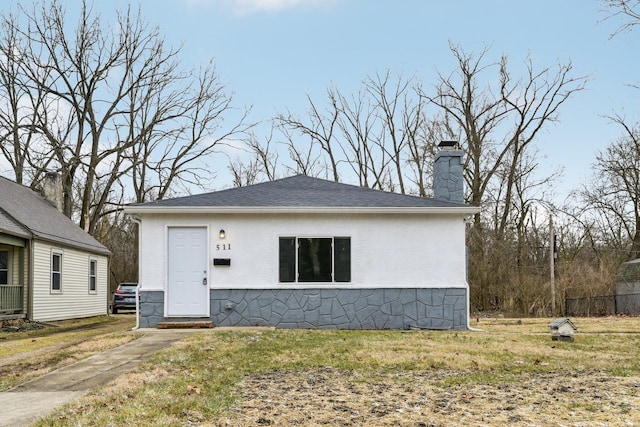 bungalow-style house featuring stucco siding, a chimney, and a front lawn