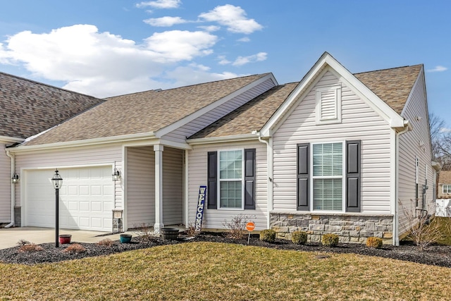 view of front of property featuring an attached garage, a front lawn, driveway, and roof with shingles