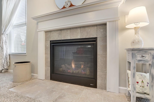 interior details featuring a tile fireplace and baseboards