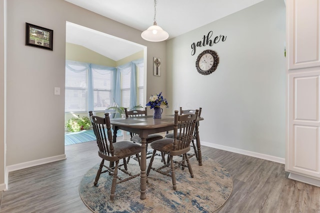 dining room with lofted ceiling, baseboards, and light wood finished floors