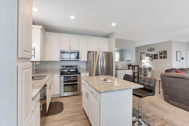 kitchen with white cabinetry, a center island, open floor plan, and stainless steel appliances