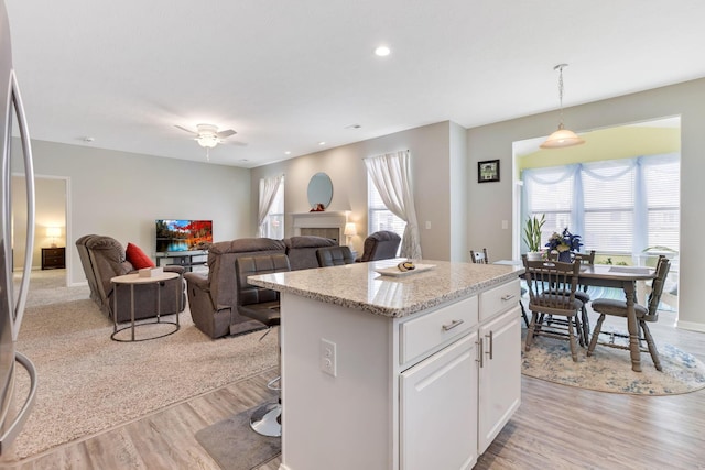 kitchen featuring a wealth of natural light, a kitchen island, a tile fireplace, and white cabinetry