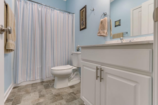 bathroom featuring a shower with curtain, stone finish floor, toilet, and vanity