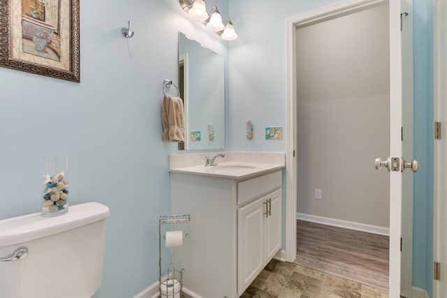 half bath featuring vanity, toilet, and baseboards