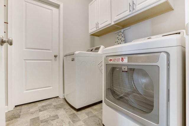 laundry room with washing machine and clothes dryer, cabinet space, and stone finish flooring