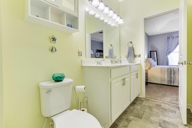 bathroom featuring vanity, baseboards, ensuite bath, stone finish floor, and toilet