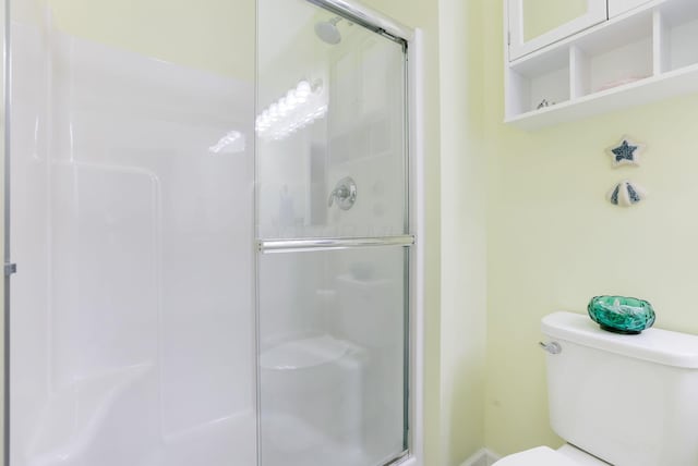 bathroom featuring toilet and a shower stall