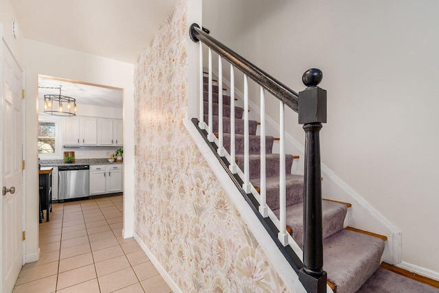 staircase with tile patterned flooring, a notable chandelier, and baseboards