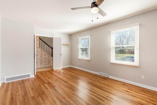 unfurnished room with stairway, a ceiling fan, baseboards, visible vents, and light wood-type flooring