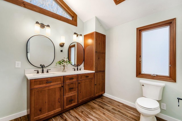 full bathroom featuring toilet, lofted ceiling, a sink, wood finished floors, and baseboards