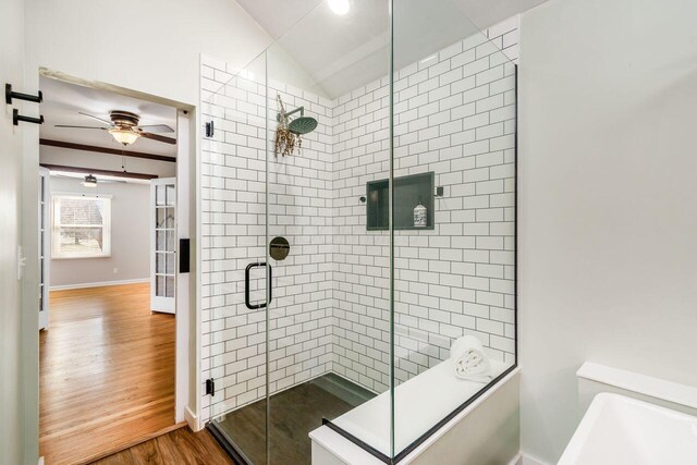 bathroom with a ceiling fan, wood finished floors, baseboards, vaulted ceiling, and a shower stall