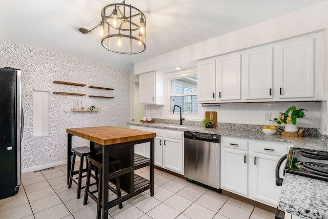 kitchen with an inviting chandelier, white cabinetry, appliances with stainless steel finishes, and wallpapered walls