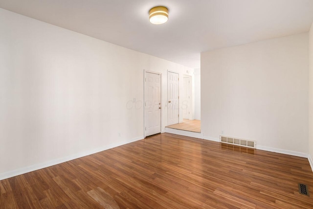 spare room featuring visible vents, baseboards, and wood finished floors