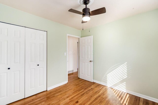 unfurnished bedroom featuring light wood-style flooring, baseboards, a closet, and ceiling fan