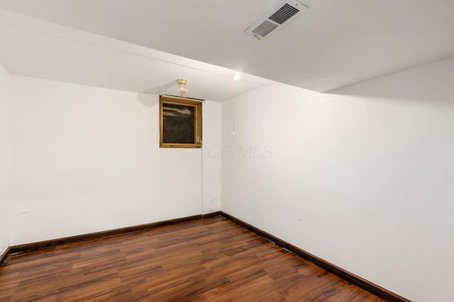 unfurnished room with dark wood-type flooring, baseboards, and visible vents