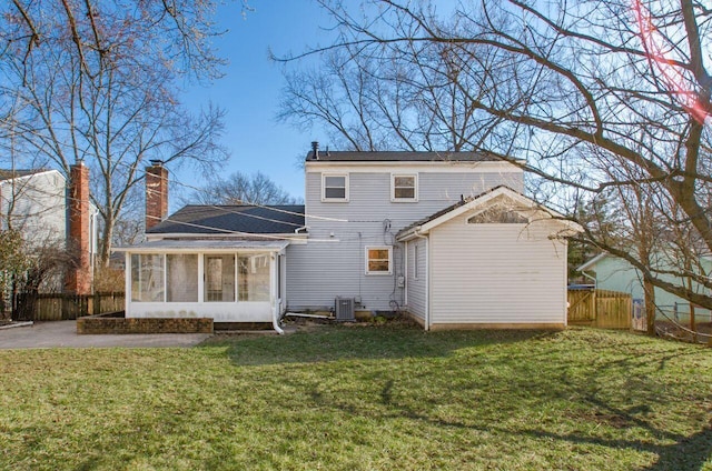 rear view of property with fence, a yard, a sunroom, a chimney, and central air condition unit