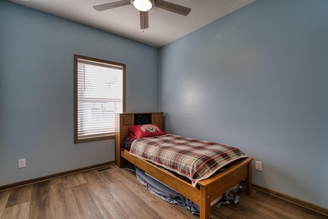 bedroom with ceiling fan, baseboards, and wood finished floors