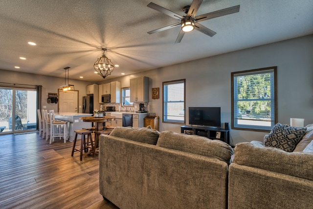 living area featuring recessed lighting, plenty of natural light, a textured ceiling, and dark wood-style floors